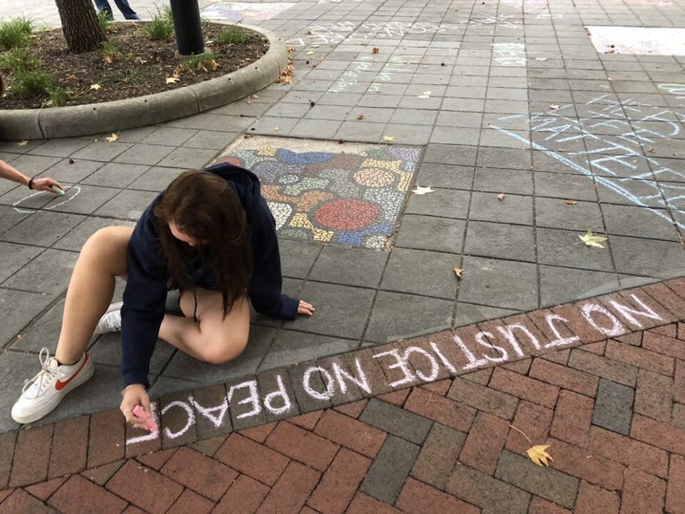 A protester writes &quot;No justice no peace&quot; on the sidewalk of People&#x27;s Park on Sept. 23, 2020. The protest was organized after only one police officer involved in the murder of Breonna Taylor was indicted. 