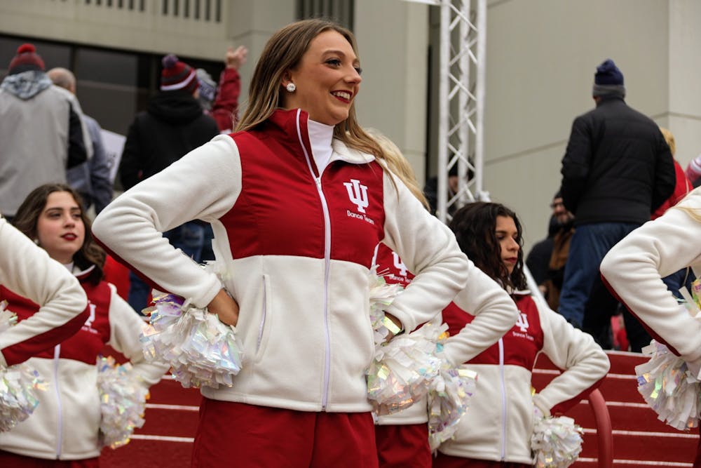 Senior Redstepper Julia Amones smiles at the crowd during the Walk, a tradition where the Marching Hundred and cheerleaders perform as the football team walks to Memorial Stadium, on Nov. 13, 2021, outside Assembly Hall. Amones said she loves her teammates and can't wait to watch and cheer them on once she graduates. 