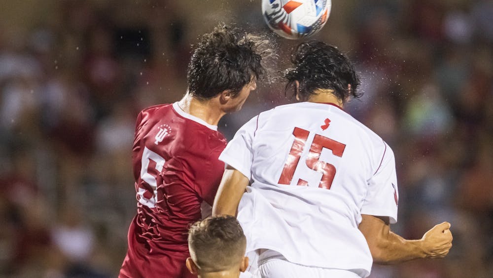 Then-junior defender Daniel Munie challenges the opposing defender in the air Sept. 17, 2021, at Bill Armstrong Stadium. Indiana tied Michigan State 1-1 on Friday.
