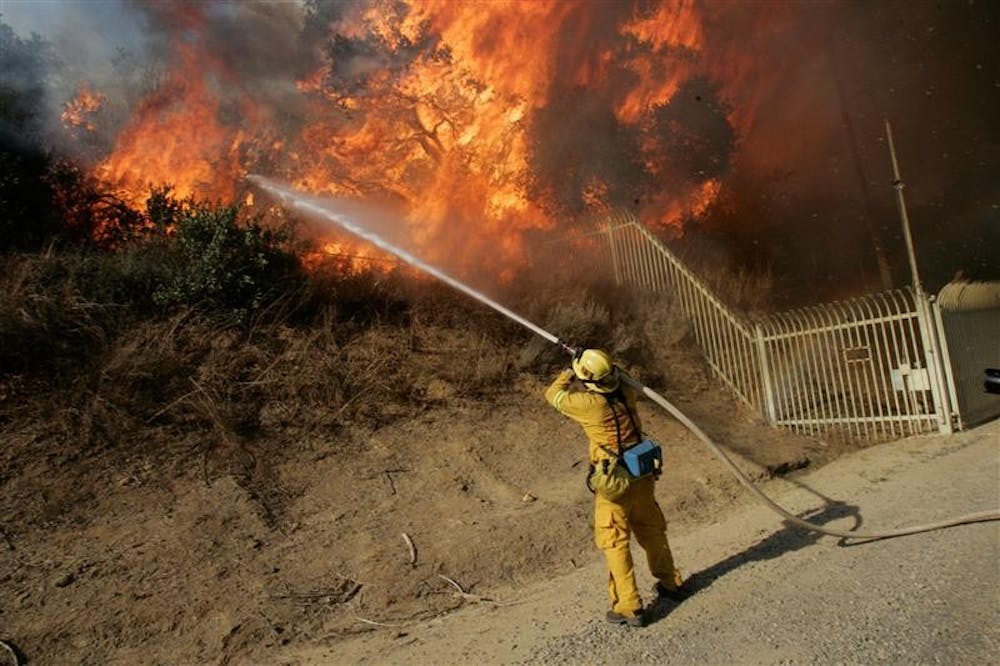 Daniel Brooks of the San Bernardino County Fire Department Grand Terrace unit fights a wildfire on Sunday in Chino Hills, Calif.  Calmer wind Sunday aided firefighters battling wildfires that have destroyed hundreds of homes in Southern California, forced thousands of residents to flee and blanketed much of the region with choking smoke. 