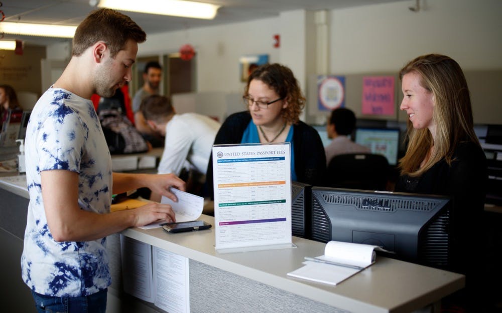 Nick Surette, left, a sophomore from Carmel, Indiana, was the first IU student to use the new passport acceptance office. Assisting him are Kristin McCormick, center, and Lorena Mendez.