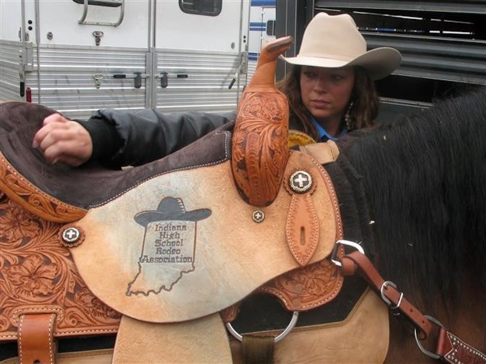 Morgan McKinney, 18, cleans her saddle as she prepares Brady, her 19-year old horse, to compete in the pole bending event at the Illinois Tri-State Rodeo. Morgan finished the season first place in pole bending for the state of Indiana last year.