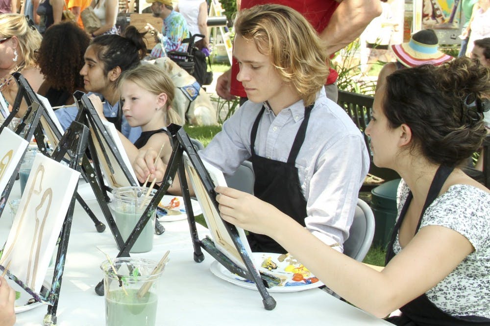 People from various ages participates in Cookies and Canvas’s painting workshop Saturday during the Arts Fair on the Square.