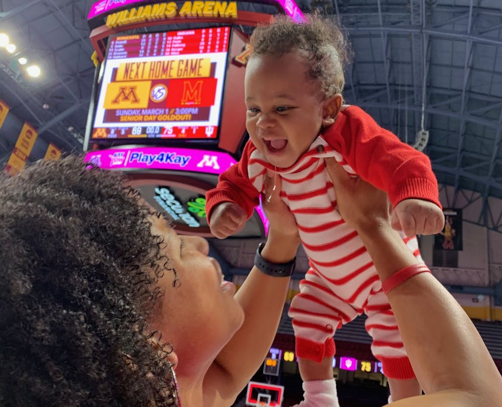 <p>IU assistant coach Janese Constantine holds her son PJ high after a win at Williams Arena in Minneapolis. Janese and PJ made a tradition of posing for a photo with the scoreboard after every road win.</p>