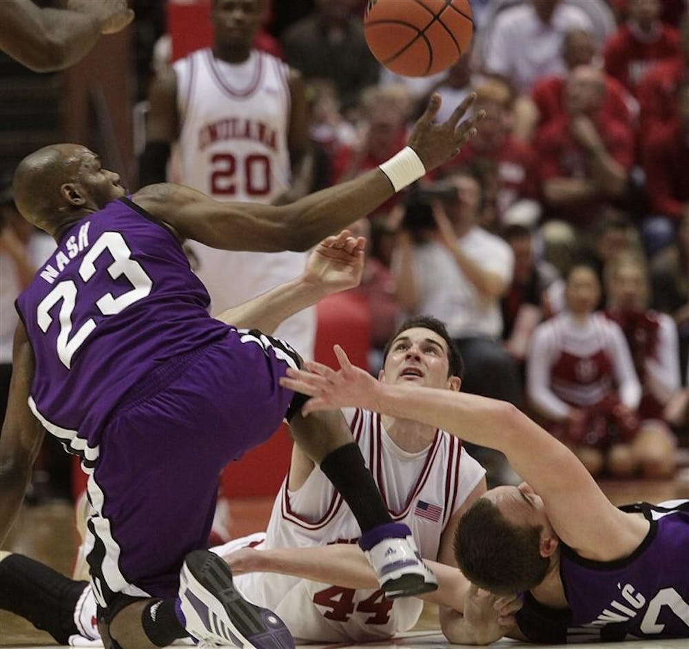 Senior forward Kyle Taber battles for a loose ball against two Northwestern players Wednesday evening at Assembly Hall. Despite taking an early lead, the Hoosiers lost to the Wildcats 75-53.