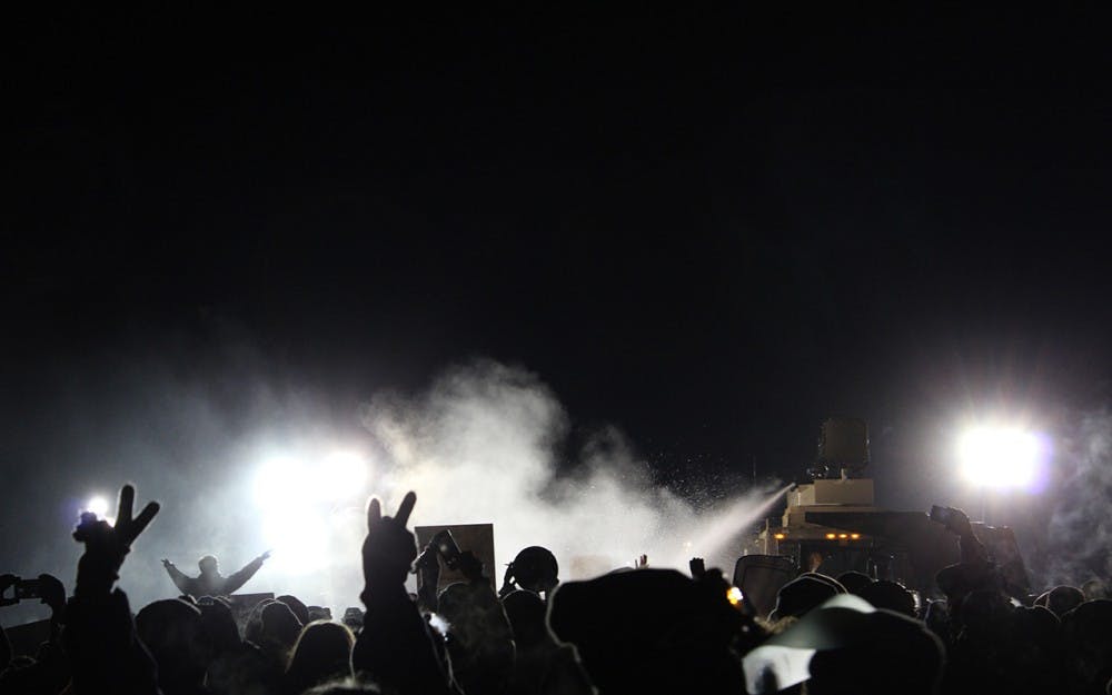 People hold up peace signs while Morton County Police spray peaceful protesters with water cannons in subzero temperatures.