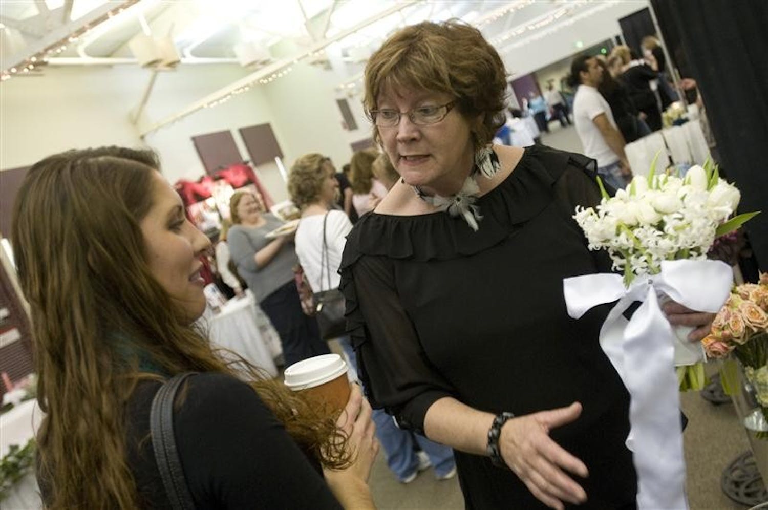 Teresa Kinder, right, of Artful Blooms Florist shows Angie Botos a bridal boquet Sunday afternoon at the Bloomington Bridal Show in the Bloomington Convention Center.
