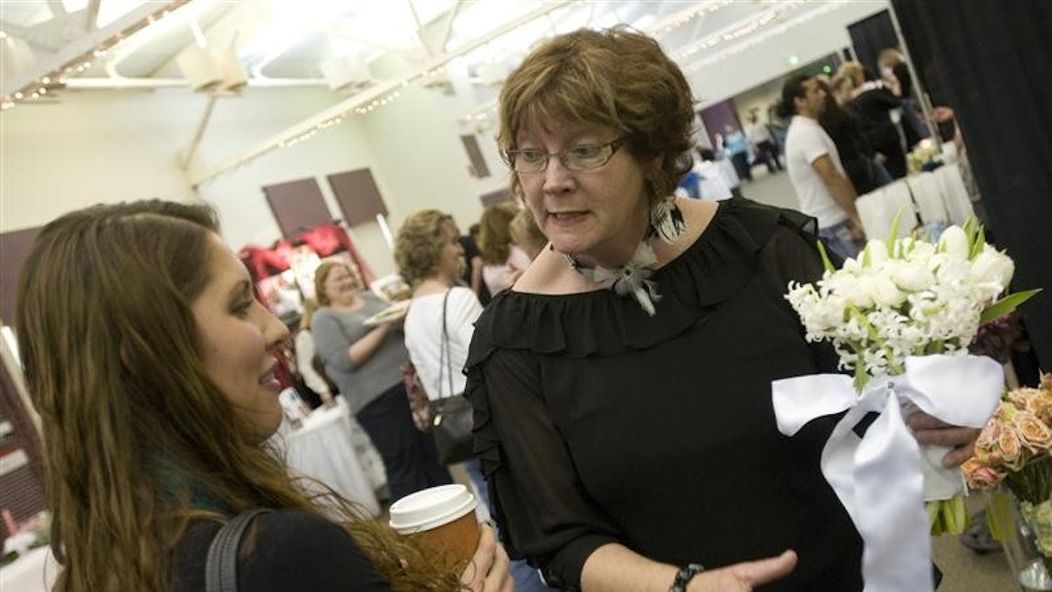 Teresa Kinder, right, of Artful Blooms Florist shows Angie Botos a bridal boquet Sunday afternoon at the Bloomington Bridal Show in the Bloomington Convention Center.