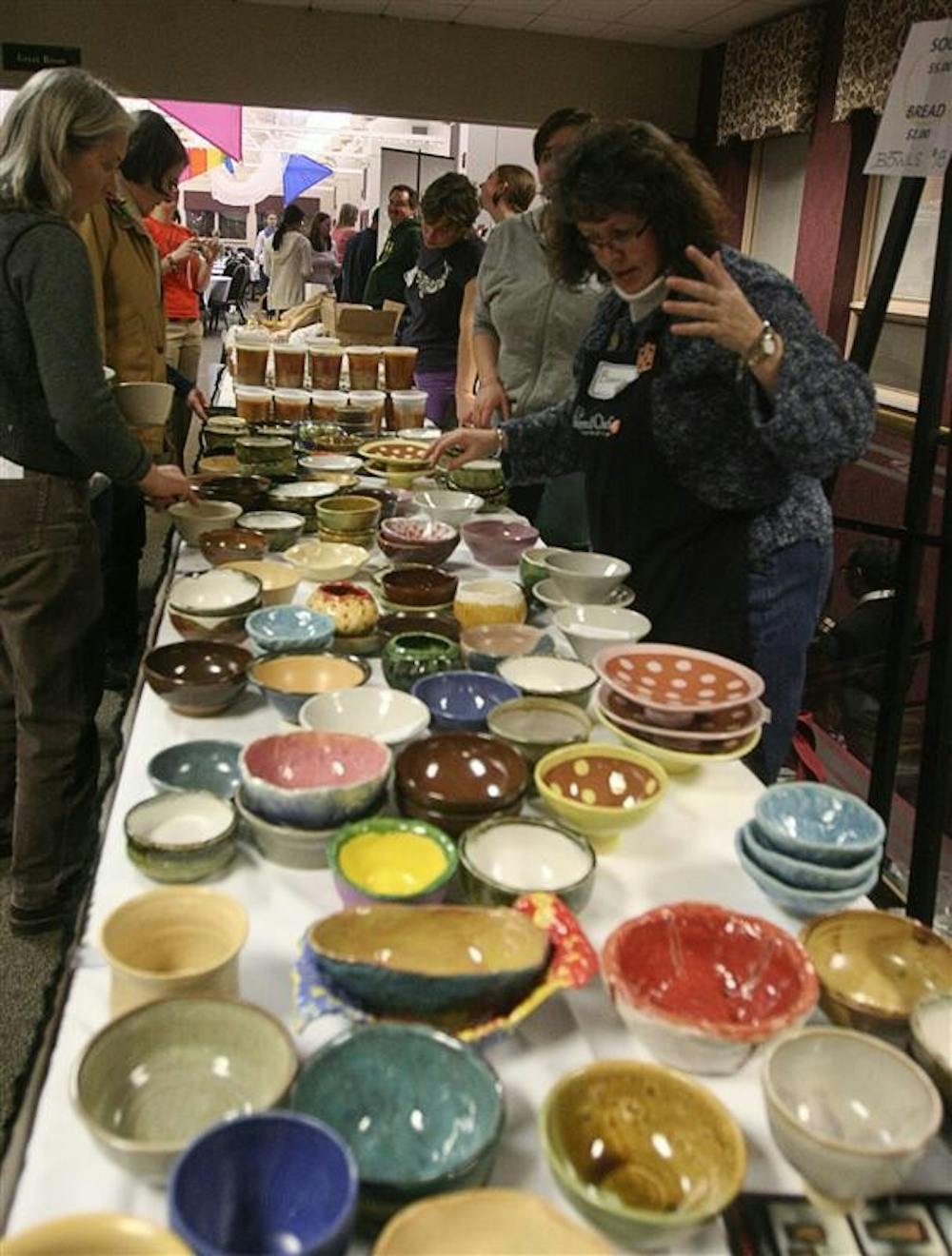 Volunteers and visiters look at the soup bowls during the Soup Bowl Benefit. The bowls are made for the event by artists, and guests can take them home as part of their donation to the event.