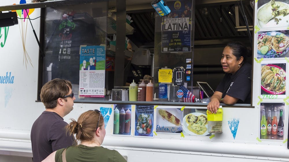 2018年6月23日，参加第36届布鲁明顿美食节的人们从Pili 's Party Taco卡车上的一名员工处订餐。19日至26日，共有42家餐厅参加了“Taste of Bloomington To-Go”活动。