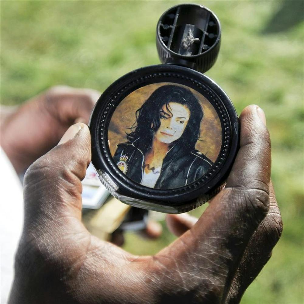 Wyatt Puryear, of Gary, holds a bottle of Michael Jackson cologne on Friday in the front yard of the pop star's childhood home in Gary. Jackson autographed the bottle when he returned to his childhood home in 2003. "It's really hurting me right now," Puryear said of the pop icon's unexpected death.
