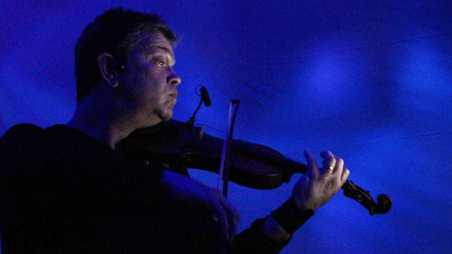 Robin Cox, musician and faculty with the Department of Music and Arts Technology at IUPUI, plays his violin during the "Nearing the End of the Hourglass" dance performance on Thursday. His wife Stephanie Nugent and her students danced nearby.