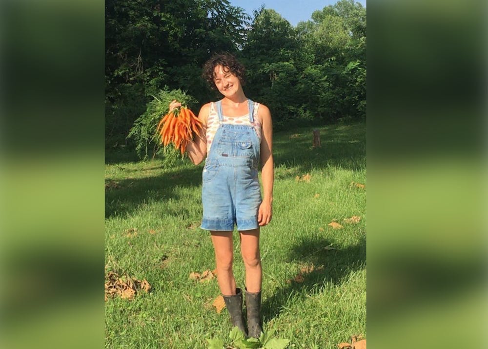 <p>Bloomington Activist Maggie Gates poses with carrots while working at Common Home Farm in summer 2021. More than 60 people, including Gates, have been indicted on charges of racketeering connected to their protest movement opposing construction of the Atlanta Public Safety Training Center, commonly referred to as “Cop City,” in Atlanta, Georgia.<br/><br/></p>