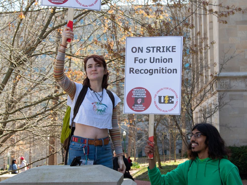 Undergraduate juniors Sophie Hall (left) and Sidd Das (right) hold strike signs at the Chemistry Building on April 14, 2022. The two are a part of Students for a New Green World and were there representing undergraduates, Hall stated.