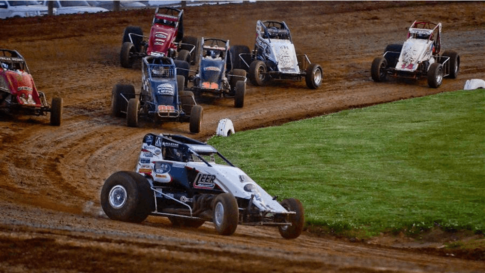 Sprint cars race around the track of Bloomington Speedway. The historic dirt track celebrates its 100th year in 2023. 