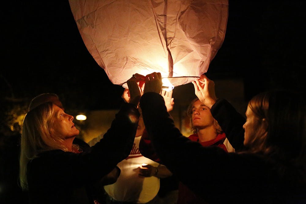 Members of Nicholas Wolfe's family; Jackie Wolfe, left, Mathew Wolfe, middle, Samantha Wolfe, right, hold up the final paper latern to be released Sunday at Showalter Fountain during a vigil for Nicholas Wolfe, an IU student who recently died.