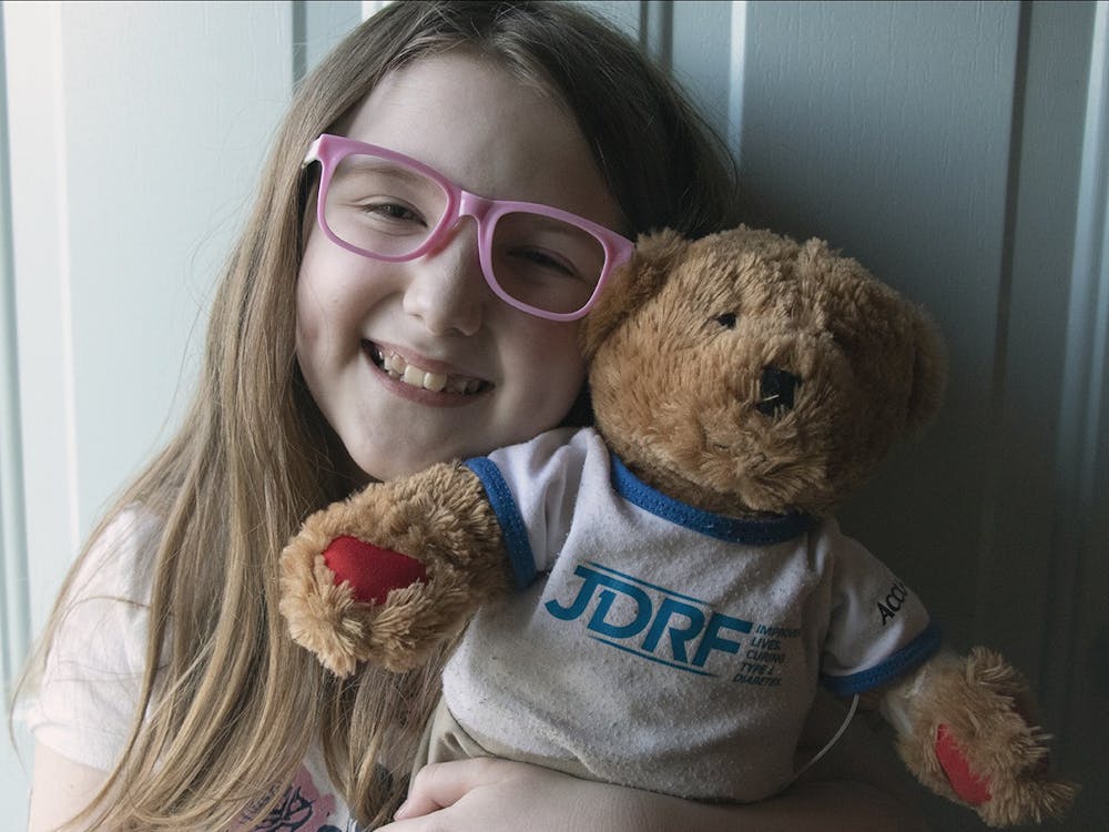 八岁的露西与她的JDRF熊合影留念。熊鲁弗斯给病人练习注射。