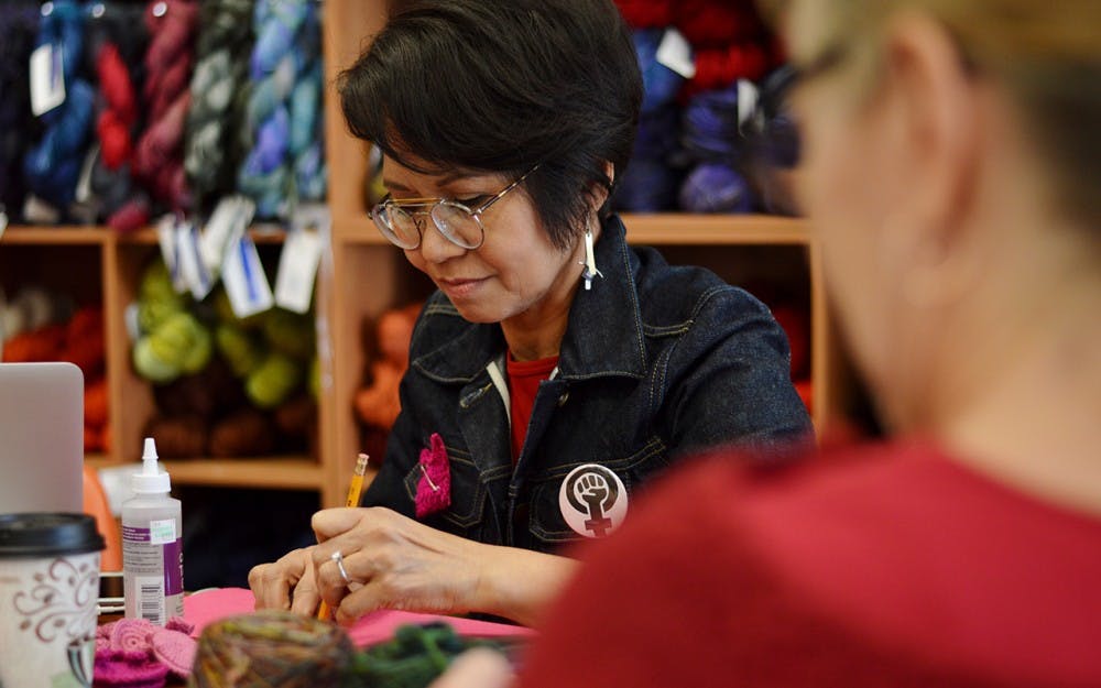 <p>Mary Ann Gingles, the owner of Yarns Unlimited, traces the felt backs for Pussyhat pins Wednesday in her shop. Gingles invited women from around the community to gather at Yarns Unlimited&nbsp;for International Women’s Day and A Day Without a Woman.</p>