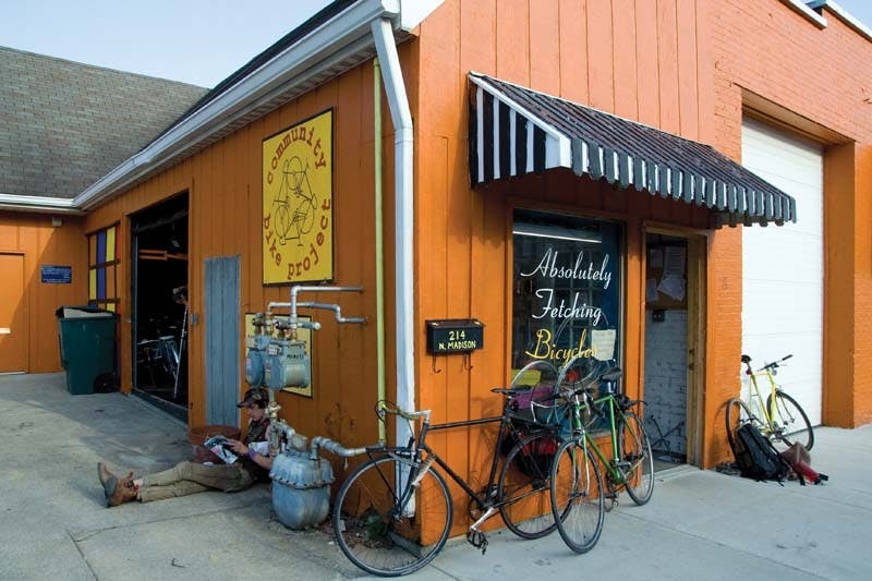 Mike Newins reads a copy of "Bicycling Magazine" outside the Community Bike Project Monday evening.