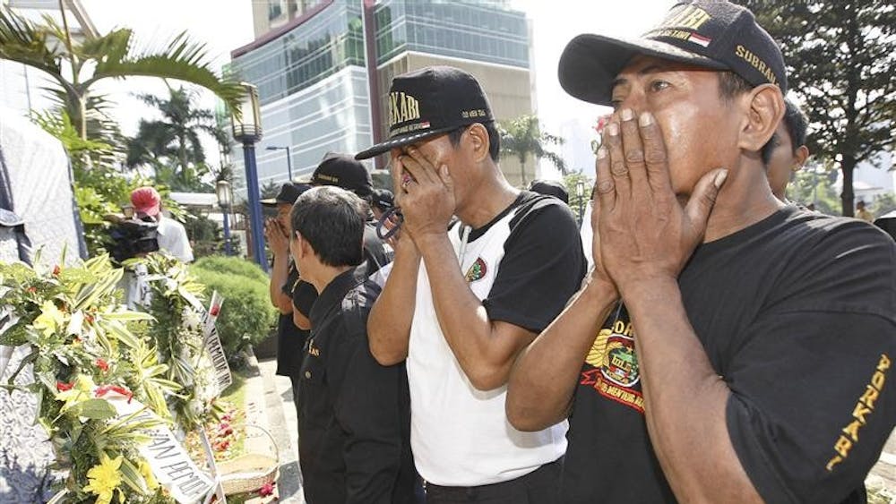 Mourners lay flowers and pray at a makeshift shrine outside the Ritz Carlton Hotel bombing site in Jakarta, Sunday July 19, 2009. Investigators are working to identify a pair of suicide bombers who attacked two American luxury hotels in Indonesia's capital on Friday July 17, and health officials confirmed at least four of the dead were foreigners.