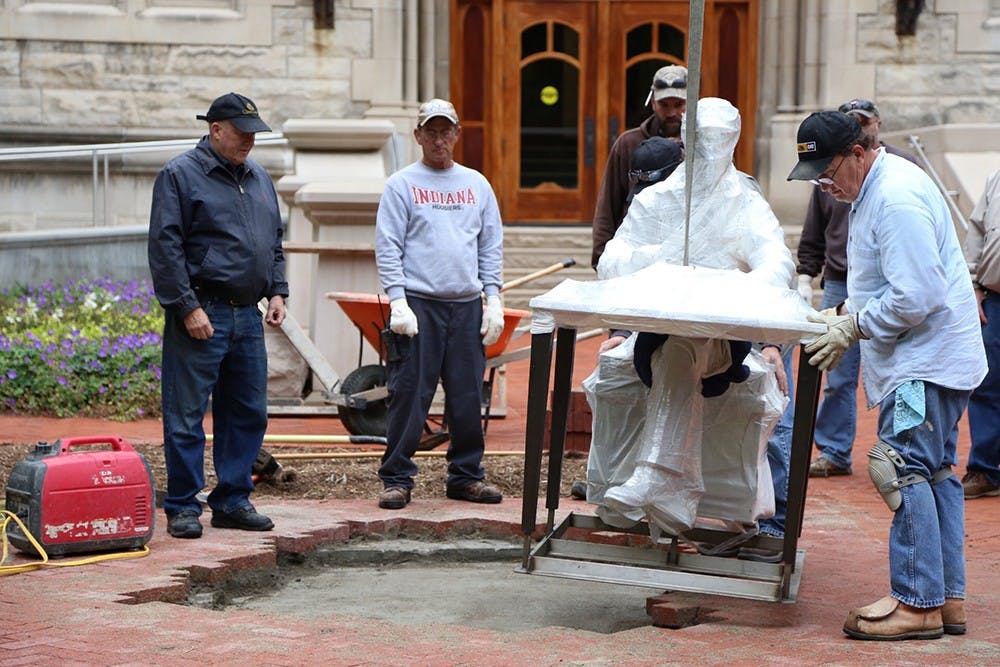 The Ernie Pyle sculpture is lowered into place in front of Franklin Hall on Thursday morning.