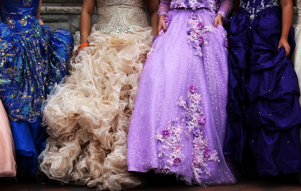 连衣裙模型作为家庭成员和朋友举起，9月26日在东吉尔科伍德大道上拍摄。根据纽约时报的数据，Quinceañera在迪斯尼等零售商处连续300美元至900美元之间的成本。