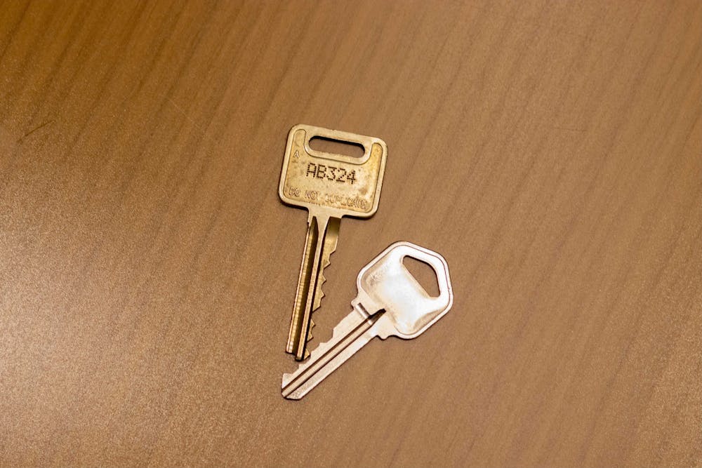 Two keys sit on a table. 