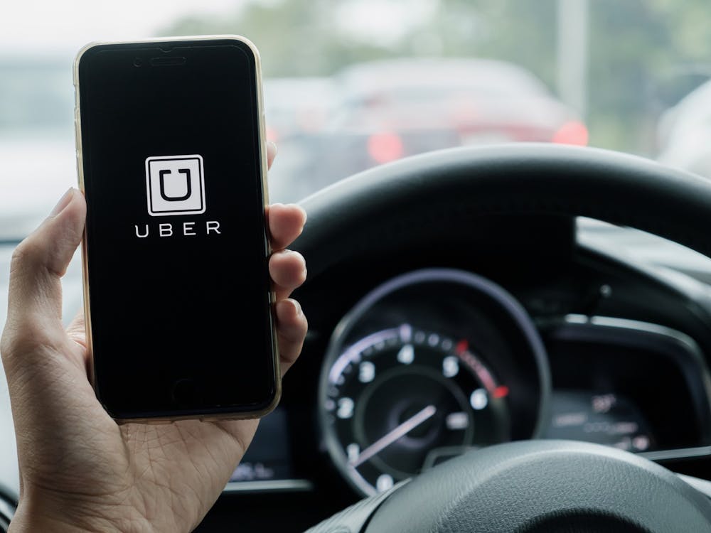 A hand holds a phone displaying the Uber app.  