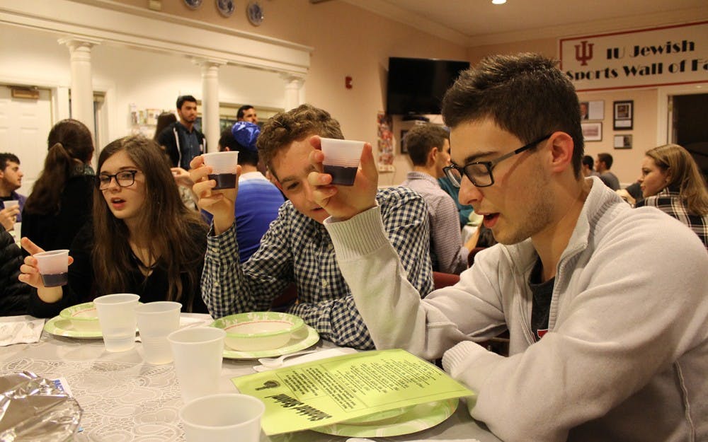 IU students&nbsp;Olivia Turi, Evan Weis and Max Gruenberg raise cups of grape juice during a pre-meal blessing Friday at the Helene G. Simon Hillel Canter.