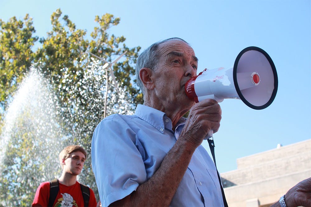 Ben Brabson, a professor of physics at IU, speaks to a group of about 50 protestors Thursday evening at Showalter Fountain. Brabson applauded IU for their energy efficient buildings but challenged the University to distance itself from the fossil fuel industry.