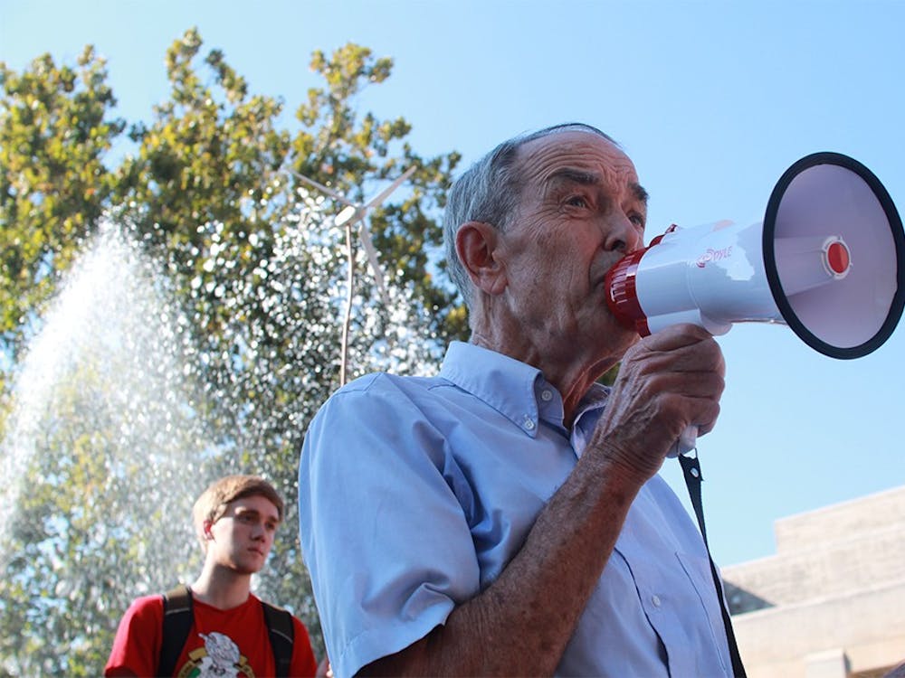 Ben Brabson, a professor of physics at IU, speaks to a group of about 50 protestors Thursday evening at Showalter Fountain. Brabson applauded IU for their energy efficient buildings but challenged the University to distance itself from the fossil fuel industry.