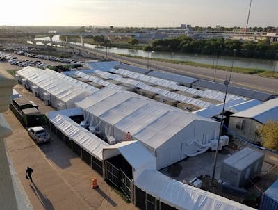 A man walks next to an immigration tent court in Laredo, Texas. With hearings expected to start this week, it still wasn&#x27;t clear if attorneys and the public would gain access to the courts, which were built by Border Patrol on the banks of the Rio Grande in South Texas.