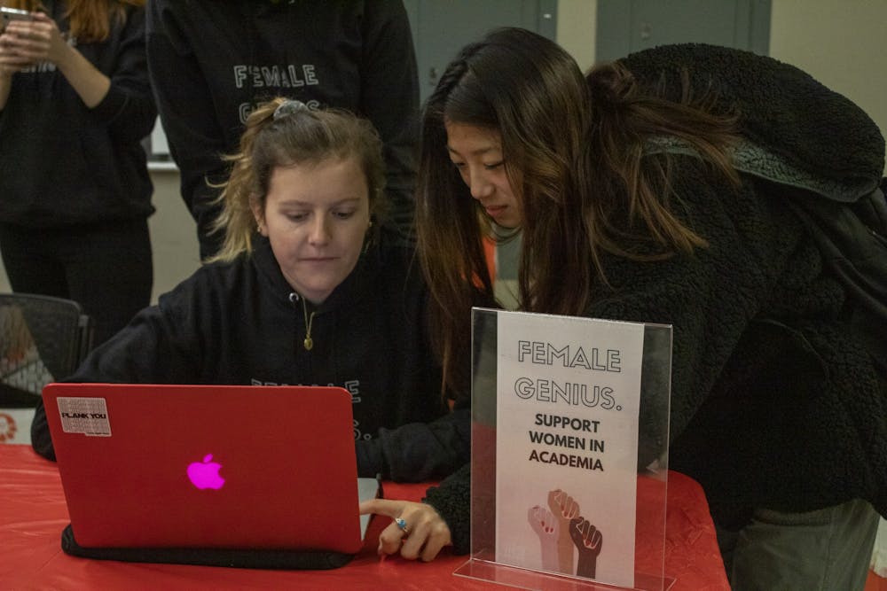 <p>Freshmen Claire Given, left, and Amber Zhao, right, pass out sweatshirts Dec. 6, 2019, in Hodge Hall. The Women In Business organization sold sweatshirts that said “Female Genius.” as a fundraiser for Girls Inc. </p>