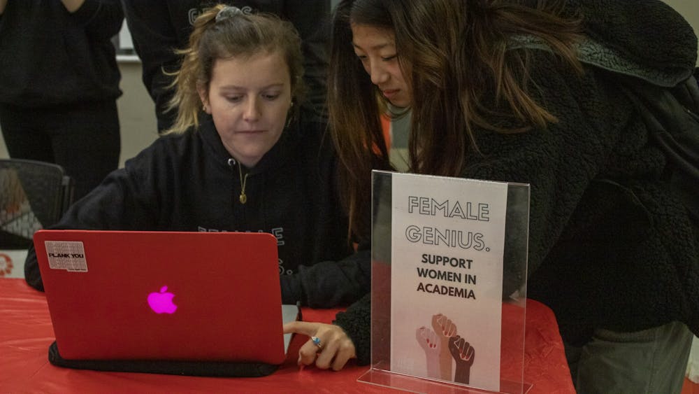 Freshmen Claire Given, left, and Amber Zhao, right, pass out sweatshirts Dec. 6, 2019, in Hodge Hall. The Women In Business organization sold sweatshirts that said “Female Genius.” as a fundraiser for Girls Inc. 