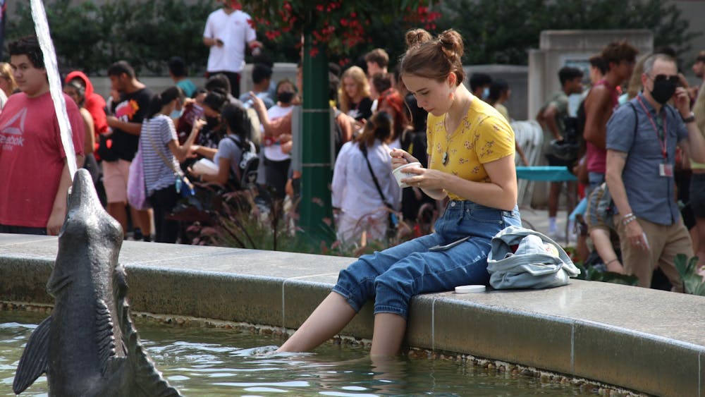 Freshman Estella Borden eats ice cream Aug. 19 while dipping her feet in Showalter Fountain during CultureFest. The welcome week event consisted of numerous booths, food trucks and live performances. 