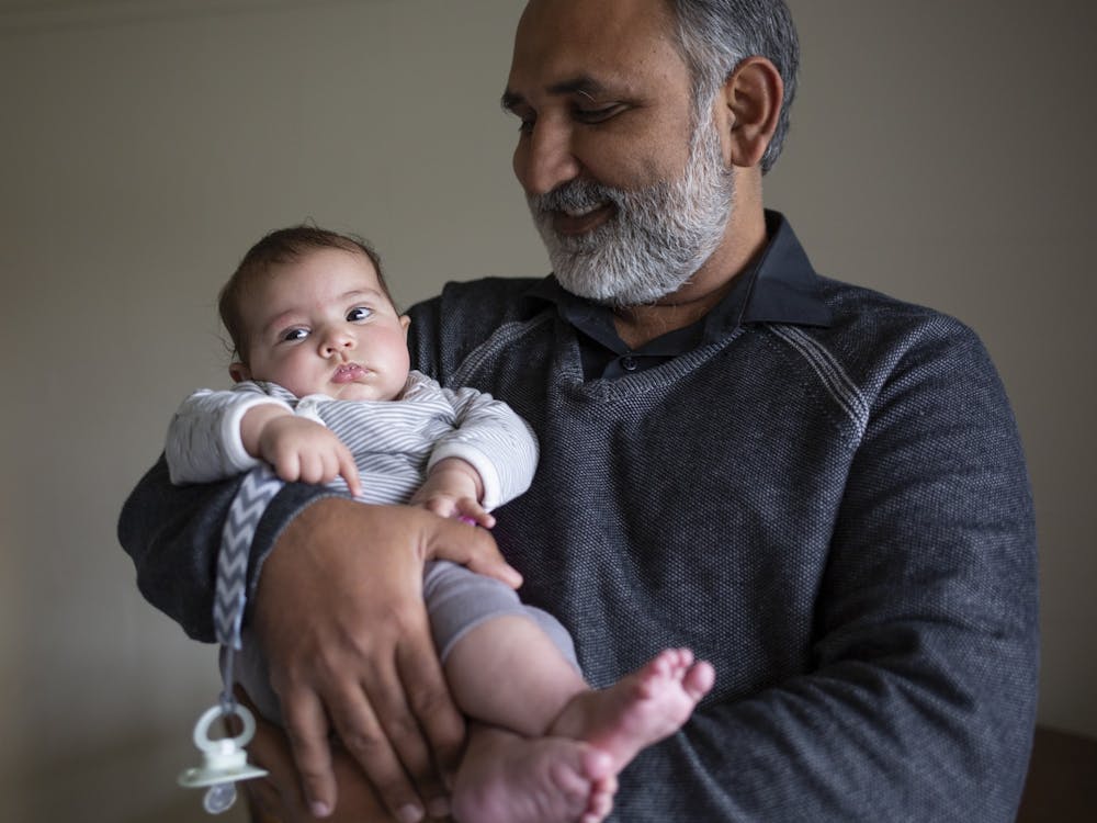 Abdul Aijaz holds his three-month-old daughter, Zohra, in his Redbud Hill apartment on March 29, 2022. Aijaz has lived in three of the buildings in IU&#x27;s northeast neighborhood since he moved from Pakistan in 2014. One  building has already been leveled, one is vacant and waiting to be razed,and his current building is slated for demolition.