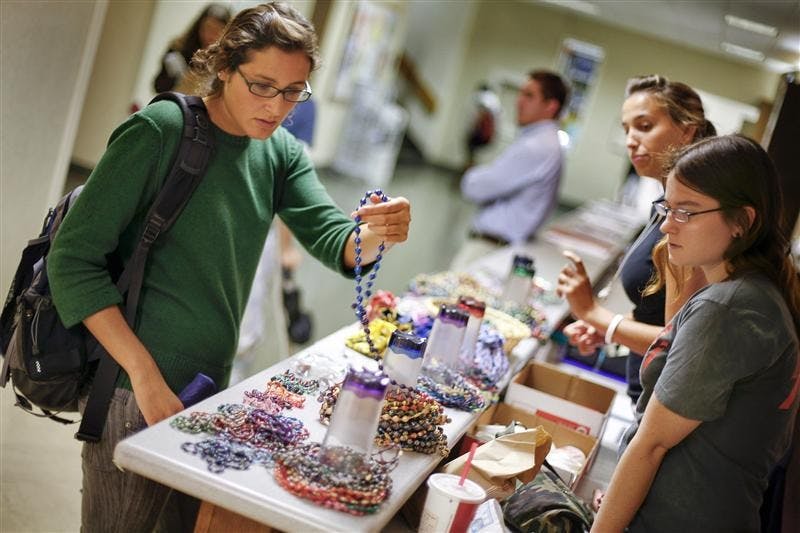 Senior Sarah Foster looks at BeadforLife necklaces with assistance from junior Lauren Plewacki and sophomore Astrid Richardson Tuesday afternoon in the Indiana Memorial Union. BeadsforLife is a nonprofit organization that helps impoverished Ugandan women lift their familes out of poverty by offering an avenue for them to produce and sell beaded jewelry made from recycled paper.