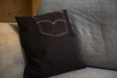 An upcycled pillow made from an old pair of jeans sits on a couch in an off-campus apartment in Bloomington.