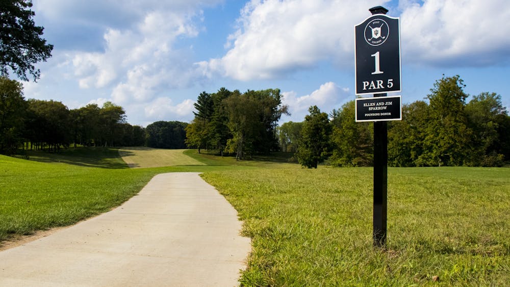Pfau IU高尔夫球场第一个洞的标志旁有一条小路。Drew Salyers，IU golf'的成员；在东诺克斯高中高年级时，他在俄亥俄州锦标赛中获得亚军。