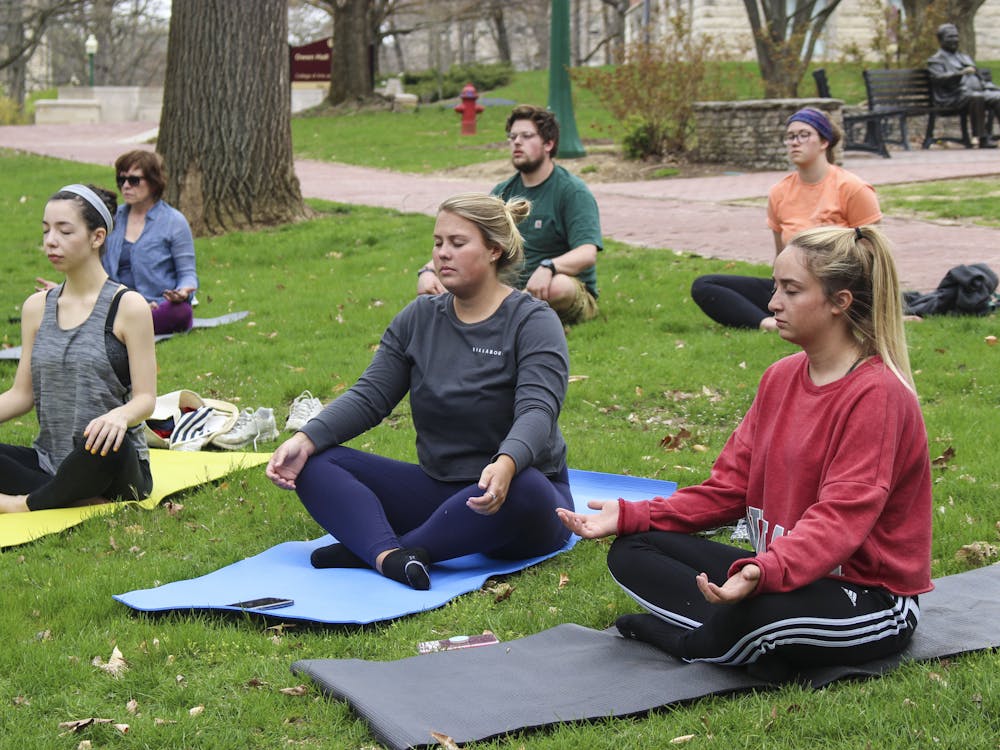 Participants of the Woodland Yoga Tour meditate April 22, 2018, in Dunn Woods. Yoga is recommended to relieve stress, relax the mind and sharpen concentration.