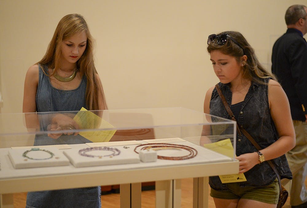 Freshman Emmaline Terry, left, and sophomore Alex Miller, right, look at a display on the second floor of the IU Art Museum during the MIX at the Museum event on Friday.