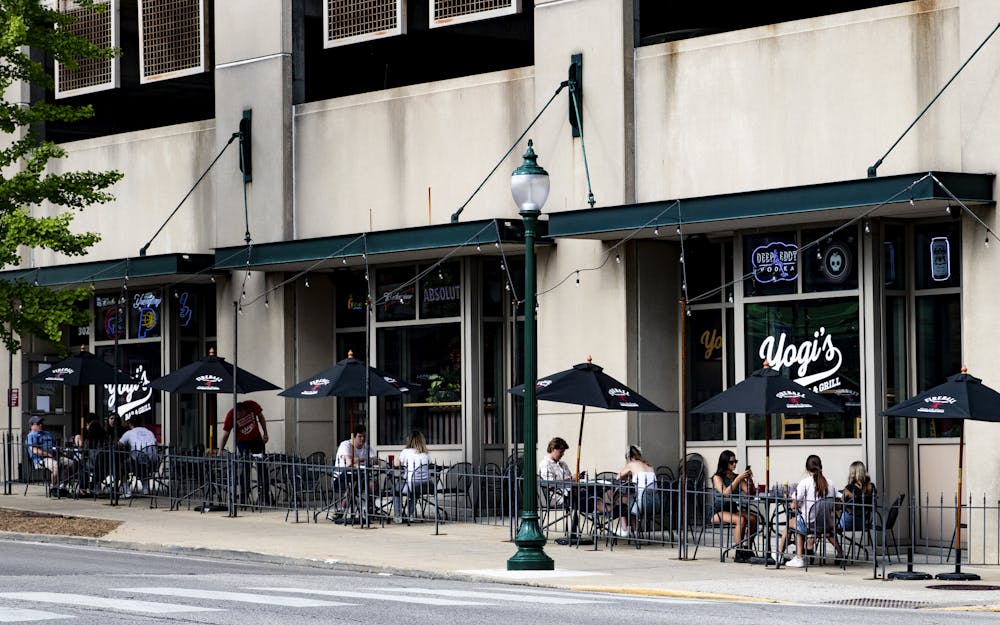 人们坐在Yogi的酒吧和5月16日在布卢明顿的烧烤之外。印第安纳州商店和酒吧开始重新打开限制和规定，以促进社会疏远。