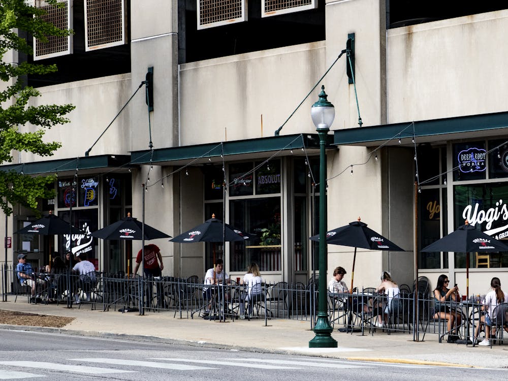 People sit outside of Yogi’s Bar and Grill on May 16 in Bloomington. Indiana stores and bars are beginning to reopen with restrictions and regulations to promote social distancing. 