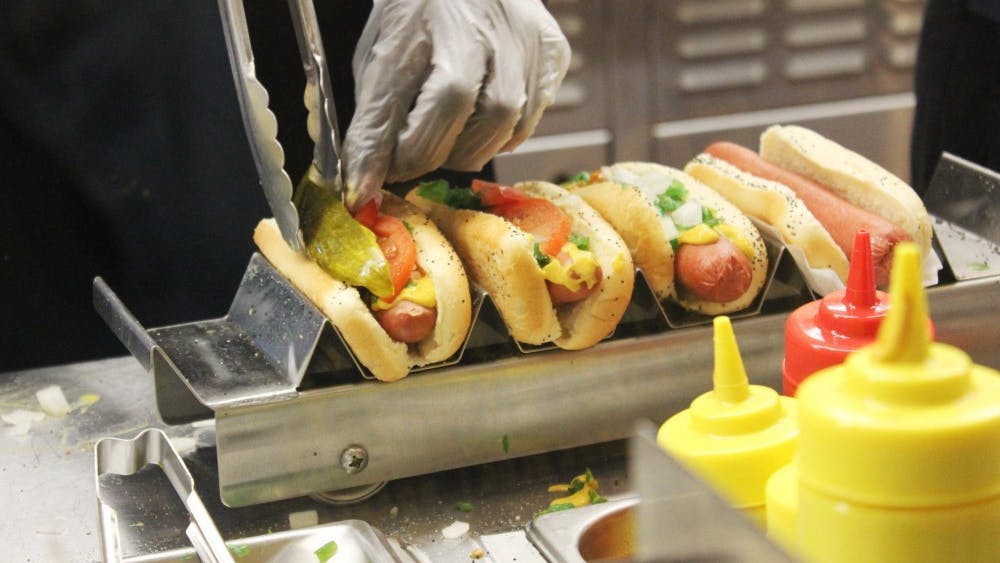 Workers at Portillo&#x27;s carefully place the toppings on hot dogs to fulfill orders. Through a job guarantee, the government would provide a job to everyone who wants and needs one.