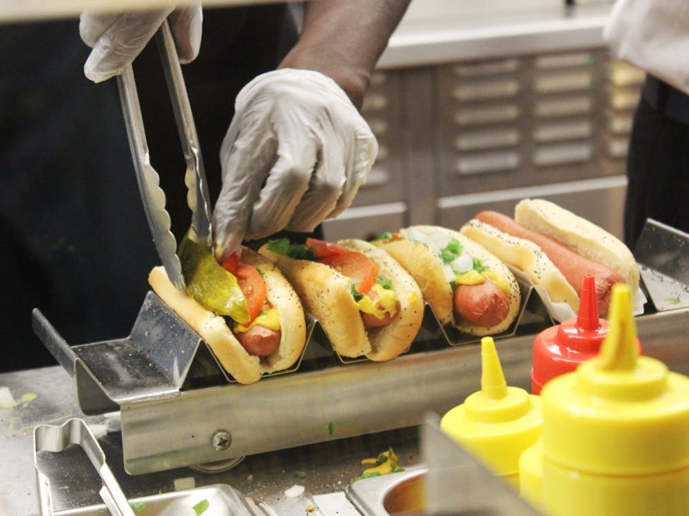 Workers at Portillo&#x27;s carefully place the toppings on hot dogs to fulfill orders. Through a job guarantee, the government would provide a job to everyone who wants and needs one.