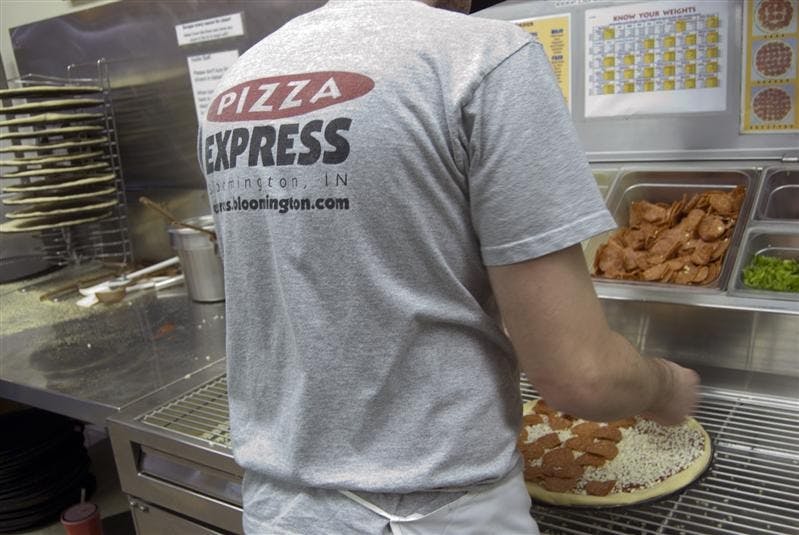 Cody Milestone prepares a pizza Wednesday evening at the Pizza Express on 10th Street. By the end of the semester, the popular pizza chain will be known as Pizza X, which can be federally trademarked so that the company can prevent future legal issues.