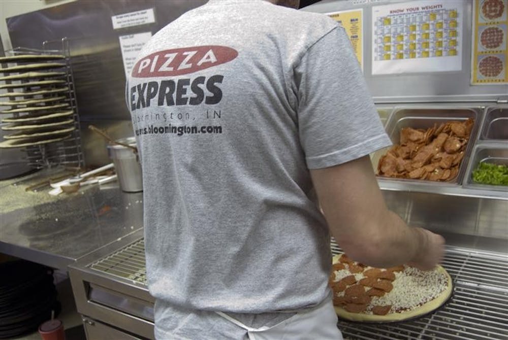 Cody Milestone prepares a pizza Wednesday evening at the Pizza Express on 10th Street. By the end of the semester, the popular pizza chain will be known as Pizza X, which can be federally trademarked so that the company can prevent future legal issues.