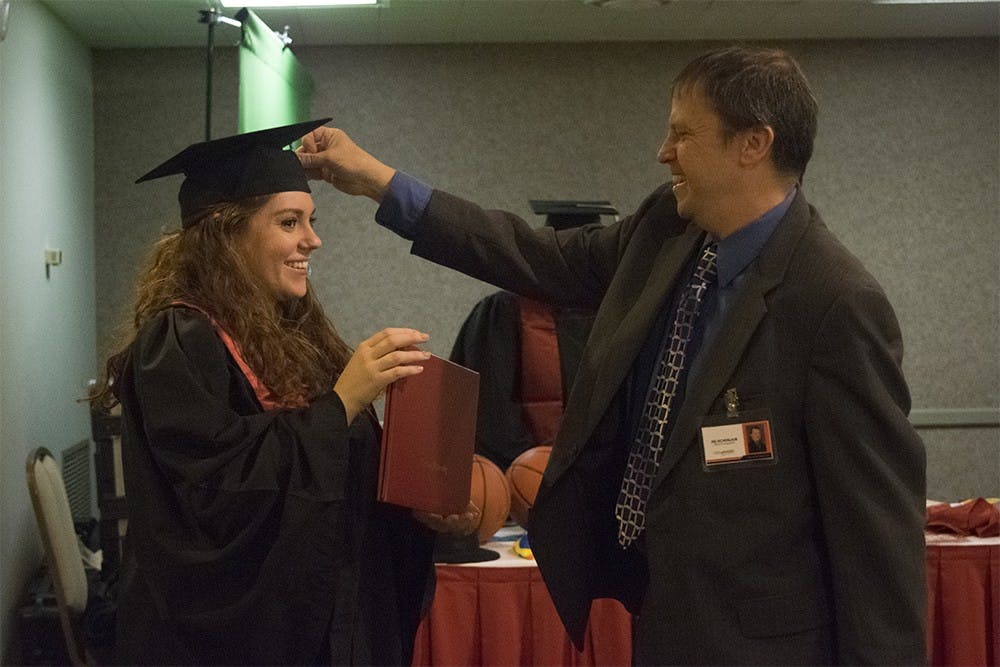 Jim Eichenlaub, graduation photographer, talks to Audre Courter about graduation pictures at the GradFair in the IMU Frangipani room Thursday afternoon. 