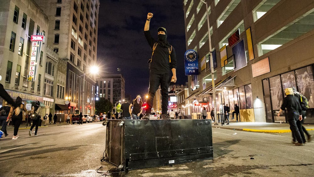 A protester stands on a knocked over vending machine May 30 in downtown Indianapolis. Protesters ran around the streets avoiding police tear gas.