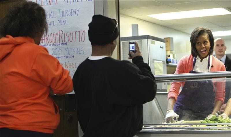 First lady Michelle Obama, right, stops to have her photo taken as she helps to hands out meals during her visit to Miriam's Kitchen Thursday in Washington. The center provides meals, case management services and housing support to nearly 250 men and women in Washington.